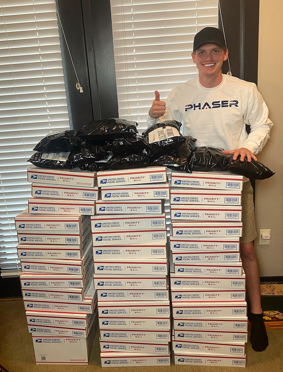 Luke Eggebraaten standing next to a pile of post office boxes from selling his phaser marketing sweatshirts